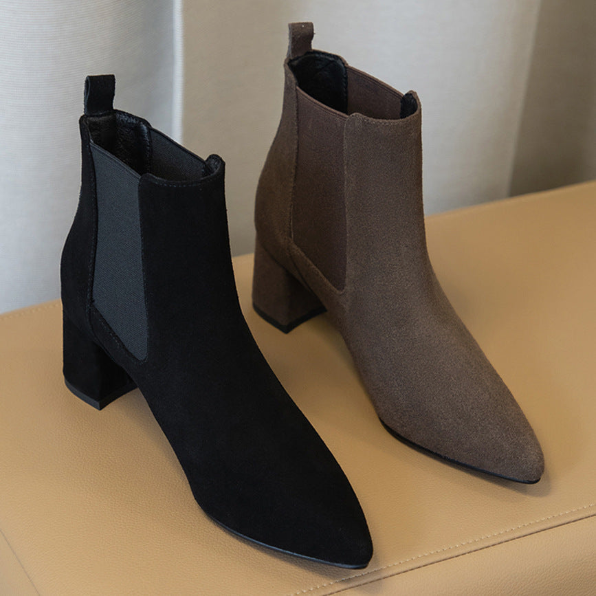 Two stylish suede ankle boots, one black and one brown, with block heels on a beige surface. Perfect for fall fashion and women's footwear trends.