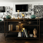 Modern living room with stylish black shelving unit, decorative lamps, geometric vases, and art books. Gallery wall and abstract art in background.