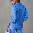 Woman in a stylish blue denim shirt and jeans, holding a beige handbag. Fashionable casual outfit, perfect for everyday wear.