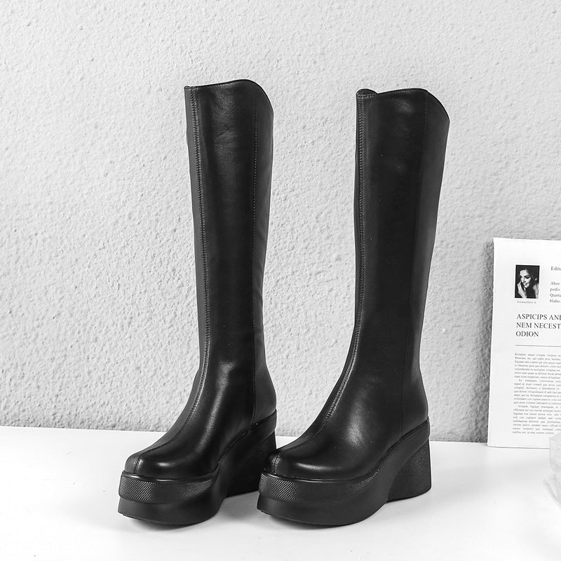 Black knee-high platform boots with chunky heels on a white surface, perfect for fashion-forward style. Women's footwear, leather boots, trendy design.