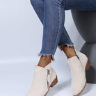 Beige suede ankle boots with side zippers paired with frayed hem blue jeans, showcasing trendy women's fall fashion footwear and casual style.