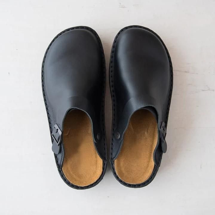 Black leather clogs with buckle strap, top view. Comfortable, stylish footwear for casual wear. Perfect for men and women. Durable and versatile shoes.