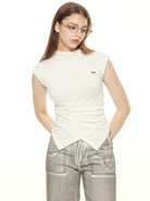 Woman wearing a stylish white sleeveless top and silver pants, accessorized with glasses. Fashionable casual outfit, modern women's clothing.