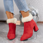 Red suede ankle boots with faux fur trim and block heels, paired with distressed jeans, on a marble floor. Fashionable winter footwear.