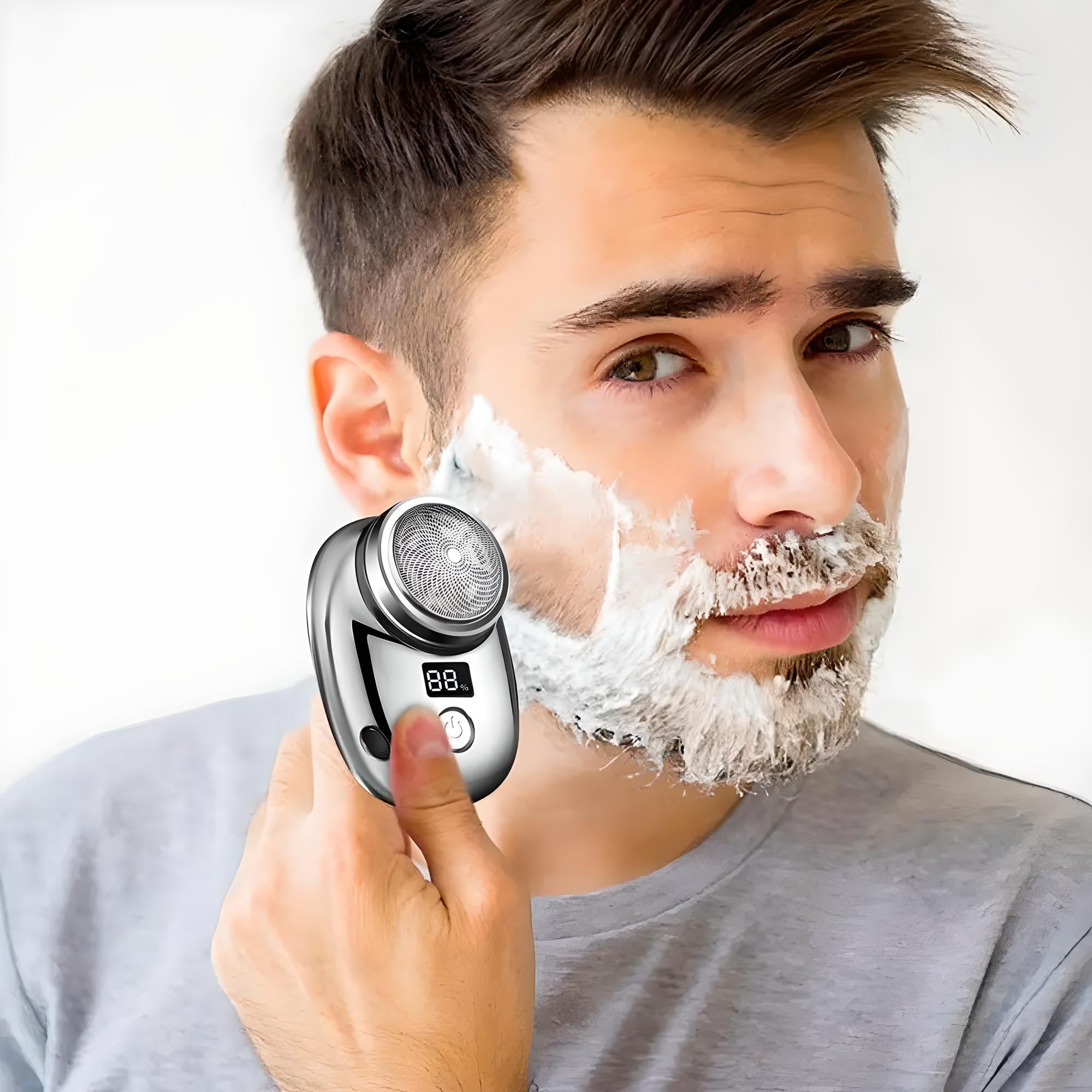 Man using electric shaver with digital display, shaving cream on face. Modern grooming tool, close-up. Ideal for men's grooming and personal care.