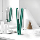 Green hair straightener on a modern white vanity with a round mirror and skincare products; sleek design, professional styling tool, beauty essentials.