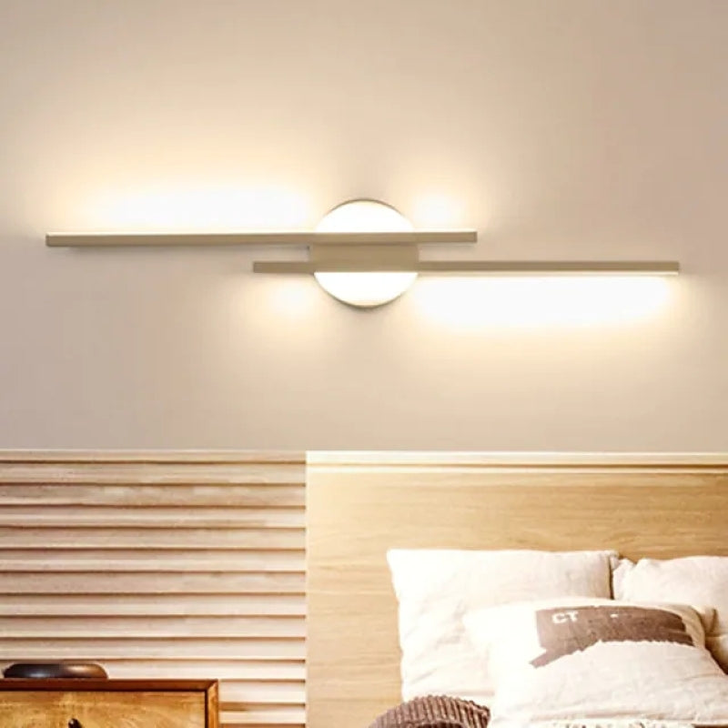 Modern wall sconce with circular base and horizontal LED light bars, illuminating a cozy bedroom. Stylish lighting fixture for contemporary interiors.