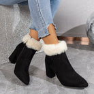 Black suede ankle boots with faux fur trim, block heels, and side zippers, paired with distressed light blue jeans on a marble floor. Fashion footwear.