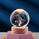 Crystal ball with engraved child holding an umbrella, illuminated on a wooden base. Decorative glass orb, unique gift, home decor, LED light display.