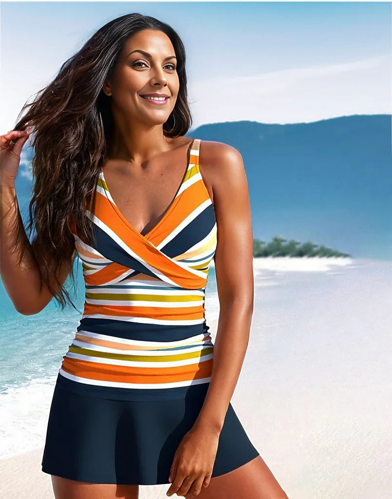 Woman in colorful striped tankini swimsuit on tropical beach, smiling with ocean and island backdrop. Summer fashion, beachwear, vacation style.