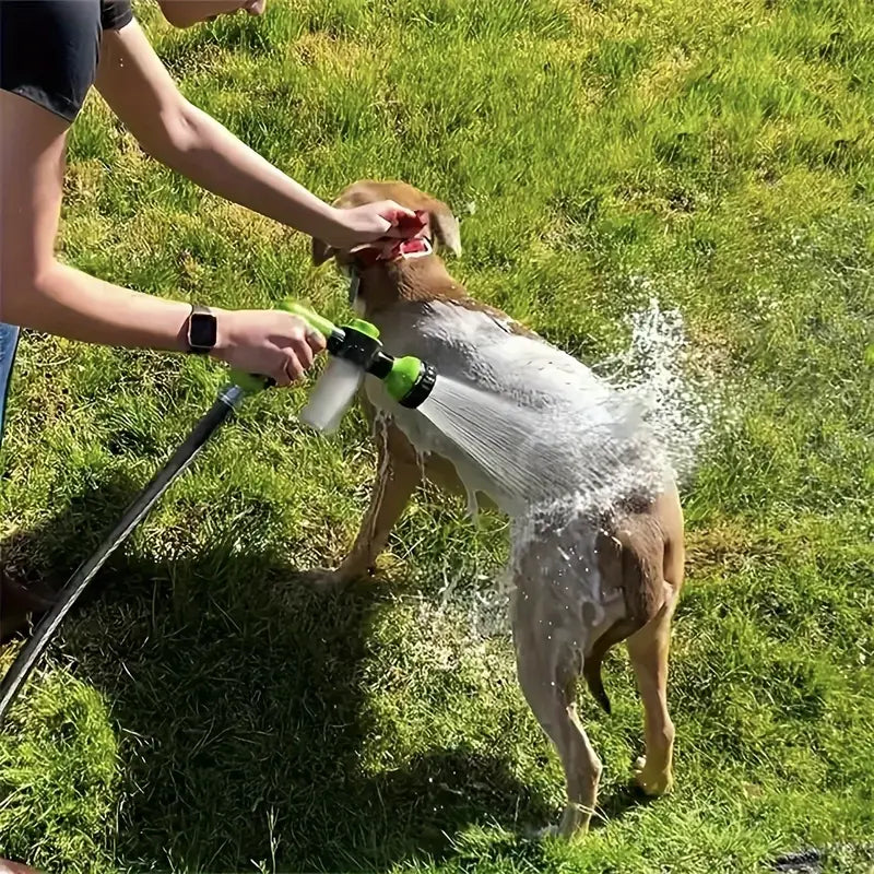 Person washing a dog with a hose and soap attachment in a sunny backyard. Pet grooming, dog bath, outdoor cleaning, summer care.