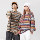 Two models wearing colorful striped knit sweaters, one in a brown cap and the other in a white beanie, showcasing trendy winter fashion.