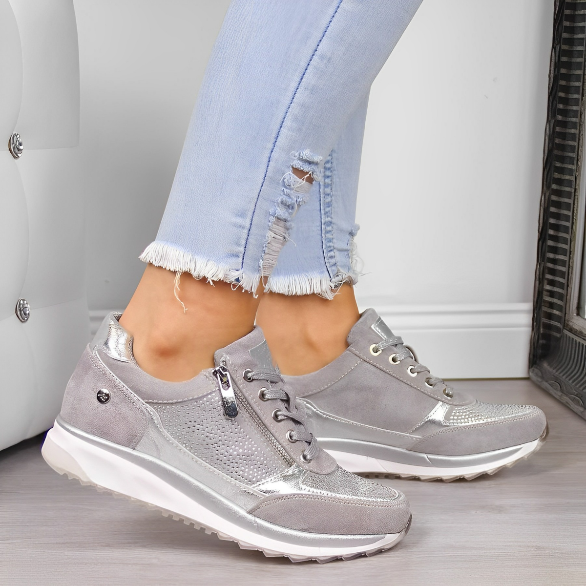 Women's silver sneakers with metallic accents and white soles, paired with light blue distressed jeans. Fashionable casual footwear for women.