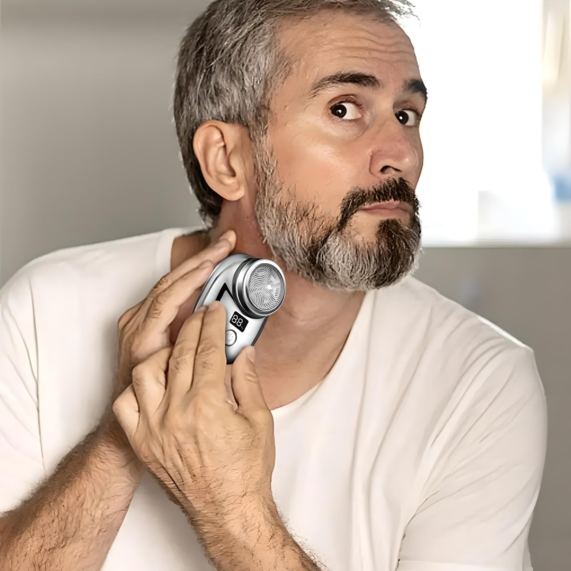 Man using electric shaver on beard, close-up. Grooming, personal care, facial hair trimming. Silver cordless razor, digital display, home bathroom setting.