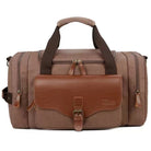 Brown leather and canvas duffel bag with multiple compartments, sturdy handles, and adjustable shoulder strap. Ideal for travel, gym, or weekend trips.