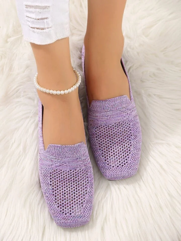 Lavender knit loafers on a white fur rug, worn with white ripped jeans and a pearl anklet. Stylish women's footwear, casual fashion.