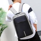 Man wearing a sleek, modern black and gray anti-theft backpack with USB charging port, ideal for travel and daily use. Stylish, secure, and functional design.