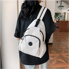 Woman wearing a stylish white backpack with multiple pockets, black accents, and adjustable straps, perfect for travel or daily use. Fashionable accessory.