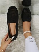 Black glitter loafers on white fur rug, worn with white ripped jeans and pearl anklet. Stylish women's footwear, casual chic fashion.