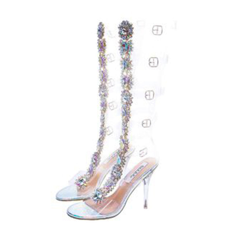 Clear knee-high boots with transparent heels, adorned with sparkling rhinestone floral embellishments, perfect for fashion-forward statement looks.