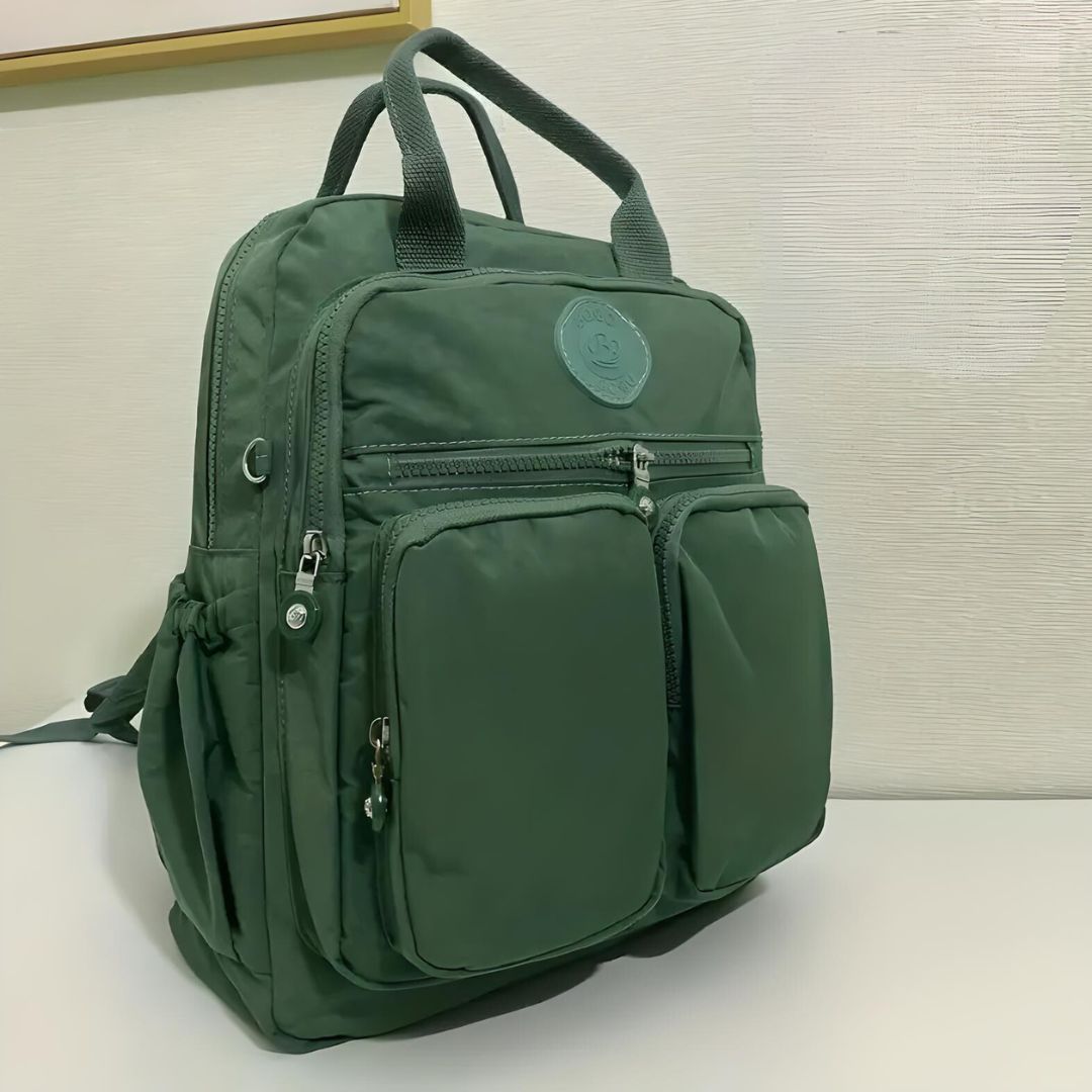 Green backpack with multiple zippered pockets, sturdy handles, and a sleek design. Ideal for travel, school, or work. Durable and stylish accessory.