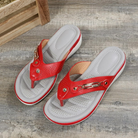 Red women's orthopedic sandals with cushioned insoles on a wooden floor, featuring a stylish design and comfortable fit for everyday wear.