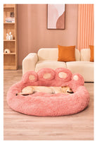 Pink plush dog bed shaped like a paw, featuring a sleeping dog, cozy pet furniture.