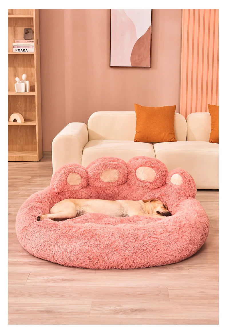 Pink plush dog bed shaped like a paw, featuring a sleeping dog, cozy pet furniture.