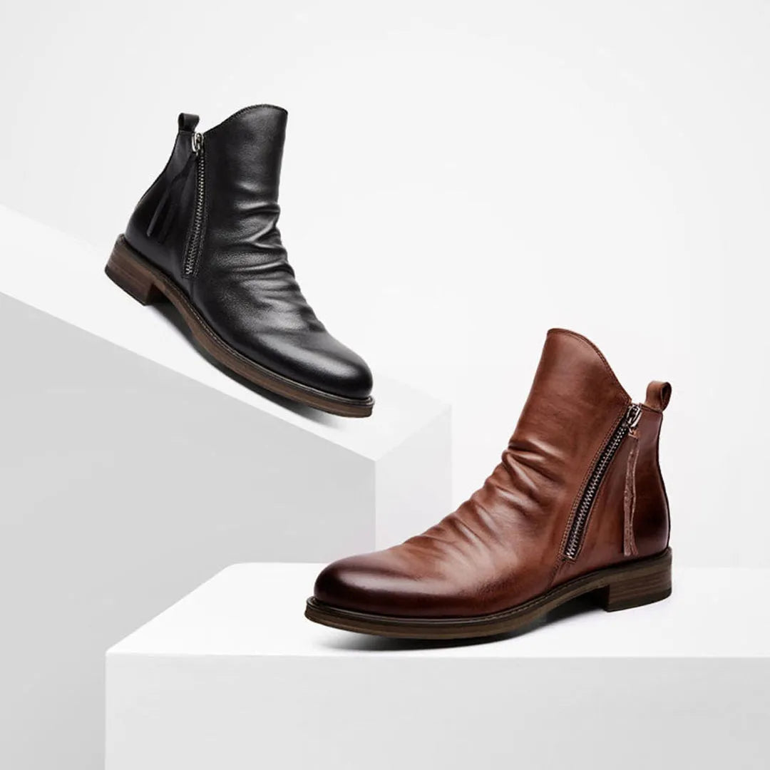 Black and brown leather ankle boots with side zippers on white steps. Stylish men's footwear, perfect for casual and formal occasions.