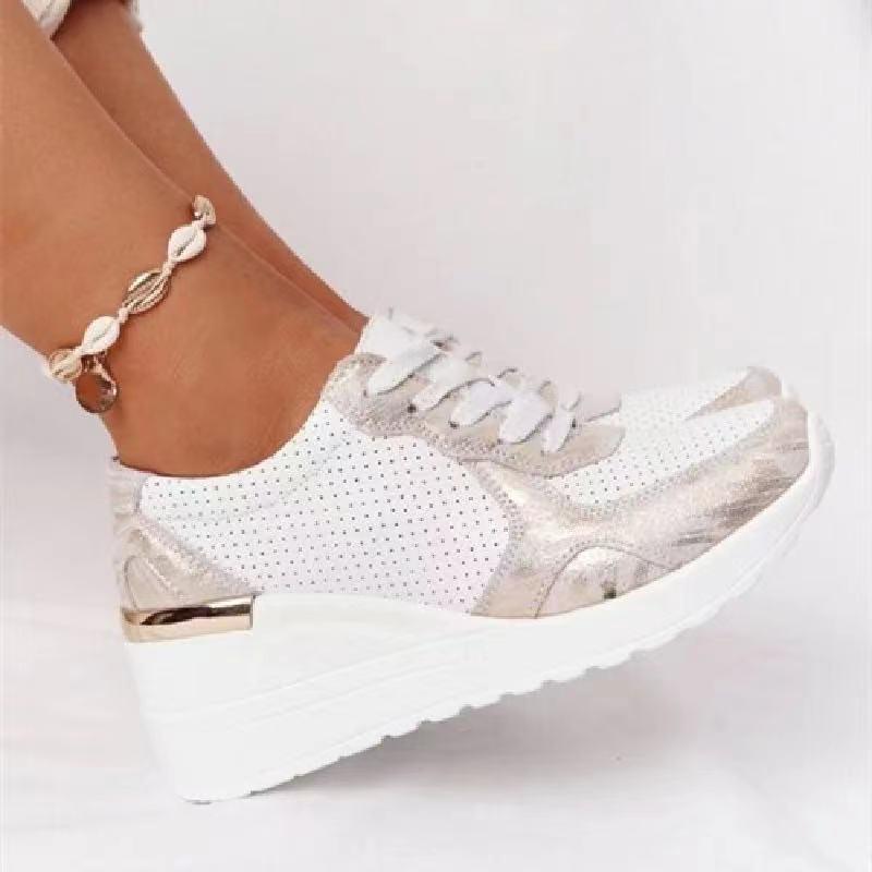 White orthopedic sneakers with gold accents, featuring a wedge heel and perforated design, paired with a stylish shell anklet. Comfortable footwear.