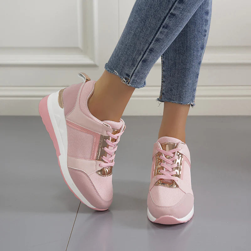 Pink orthopedic sneakers for women, featuring a stylish design with gold accents, worn with blue jeans. Comfortable footwear for pain-free walking.