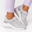 Women's orthopedic sneakers in light gray with white soles and metallic accents, designed for comfort and style, perfect for pain-free walking.