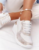 White orthopedic sneakers with gold accents, featuring a comfortable wedge sole. Ideal for pain-free walking. Fashionable footwear for women.