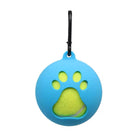 Blue silicone dog ball holder with paw print design, featuring a yellow tennis ball inside. Pet accessory with carabiner clip for easy attachment.