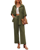 Woman wearing an army green two-piece outfit with a button-up shirt and wide-leg pants, holding a woven clutch. Fashionable casual attire.