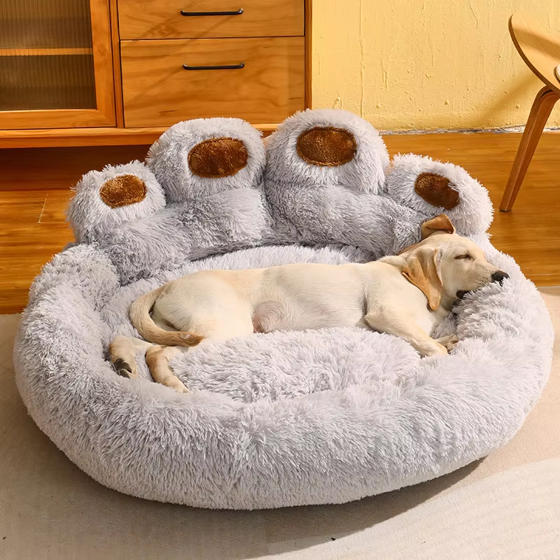 Dog sleeping on a cozy, plush paw-shaped pet bed in a modern living room. Luxurious, soft, grey pet bed for dogs. Comfortable, stylish dog furniture.