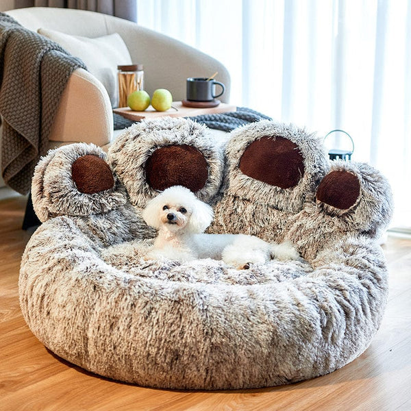 Fluffy dog bed shaped like a giant paw, featuring a small white dog resting comfortably. Cozy pet furniture, plush design, perfect for small breeds.