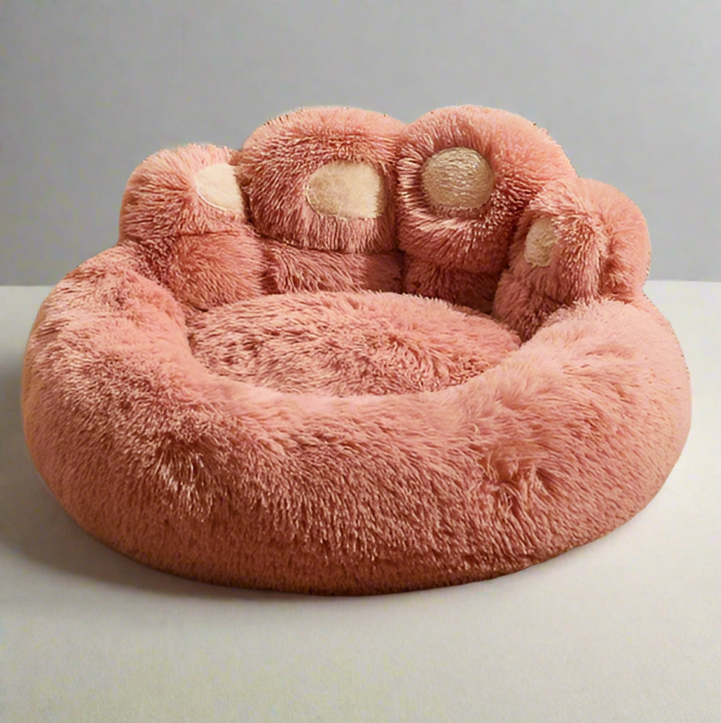 Plush pink dog bed shaped like a paw, featuring soft, fluffy material for pet comfort. Ideal for small to medium dogs. Cozy pet furniture.