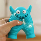 Blue monster-shaped dog chew toy with textured surface, held in hand. Durable pet toy for dental health and interactive play.