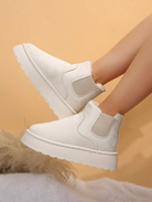 White platform ankle boots with ribbed elastic side panels and faux fur lining, set against a beige background. Fashionable women's footwear.