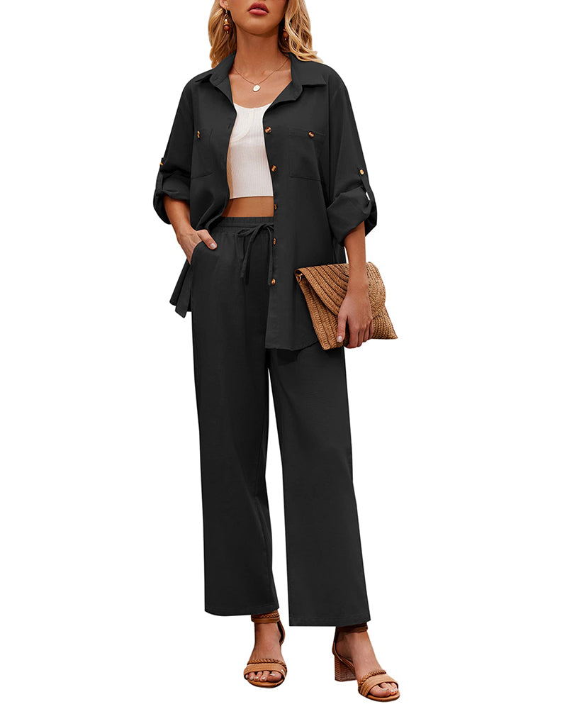 Woman in stylish black two-piece outfit with button-up shirt and wide-leg pants, holding a woven clutch. Fashionable casual wear for women.