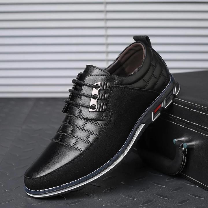 Men's black leather dress shoe with quilted pattern, lace-up design, and white sole. Stylish formal footwear for business or casual occasions.