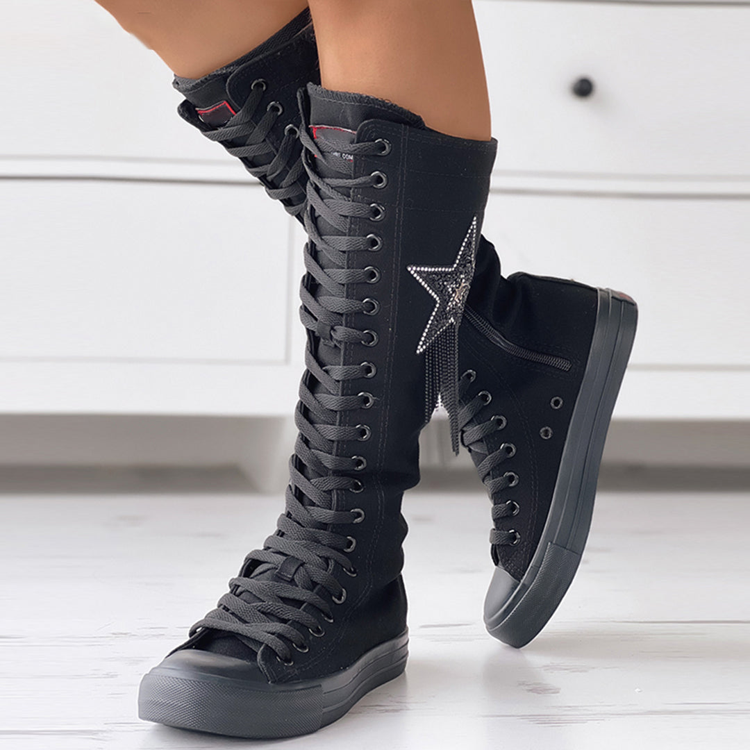 Black knee-high lace-up sneakers with star embellishment, rubber soles, and canvas material. Stylish footwear for casual fashion and streetwear trends.