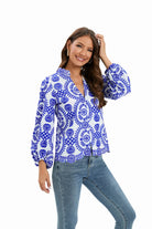 Woman wearing a blue and white floral blouse with long sleeves, paired with blue jeans. Fashionable casual outfit, perfect for spring or summer.