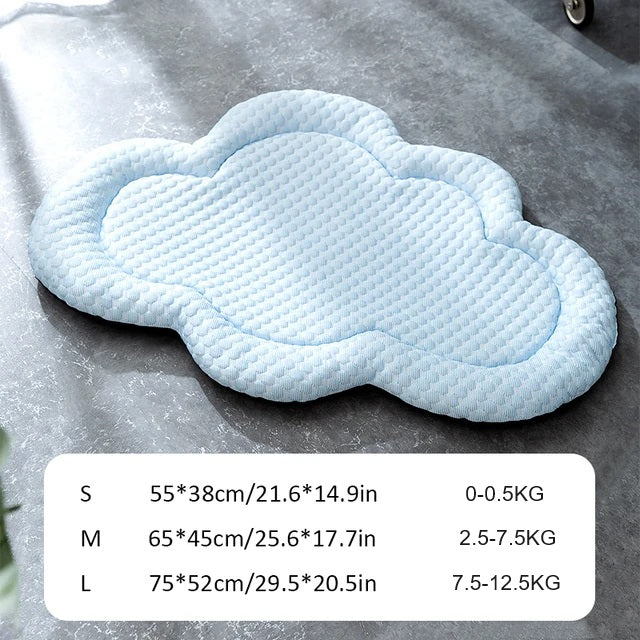 Cloud-shaped cooling dog mat on a gray surface, available in small, medium, and large sizes. Ideal for pet comfort and temperature regulation.