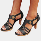 Black strappy high-heeled sandals with cork heel, featuring gold buckle accents. Stylish women's footwear for summer fashion and casual elegance.