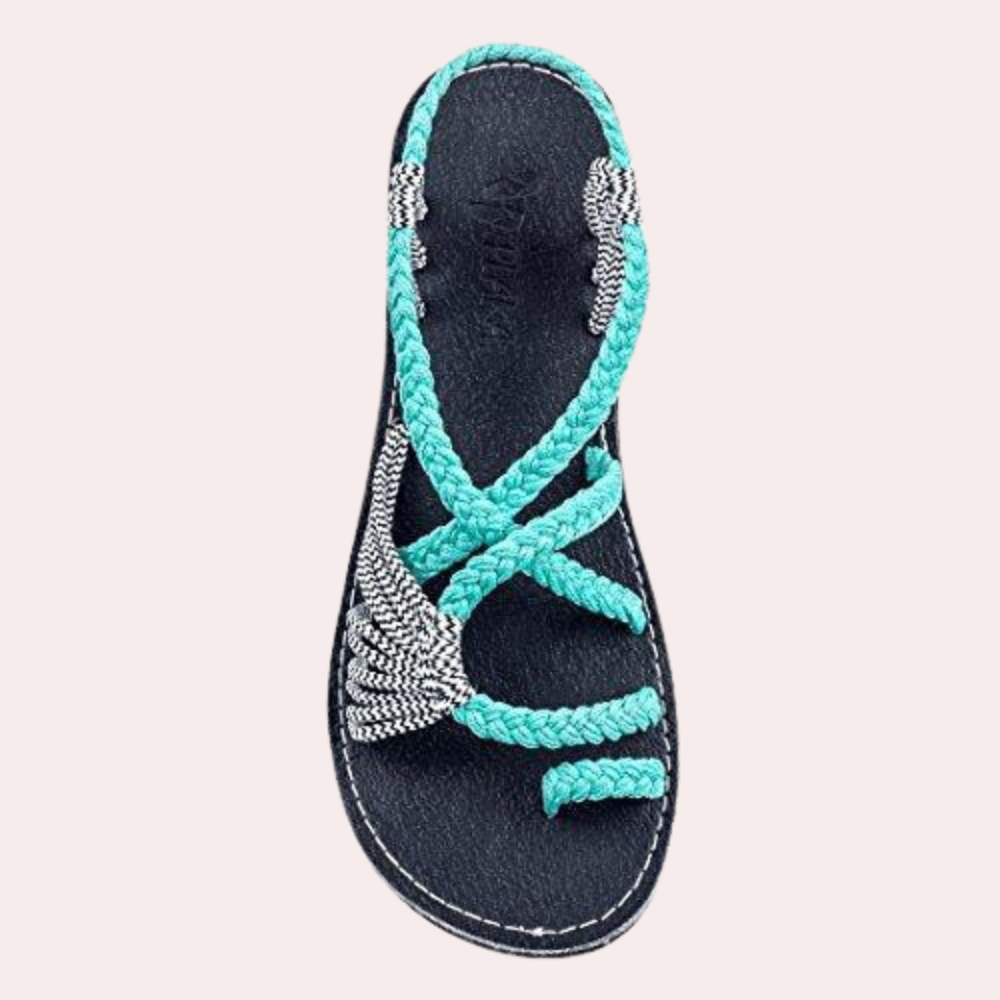 Blue and white braided sandal with intricate beading, featuring a flat sole and open-toe design. Perfect for summer fashion and beachwear.