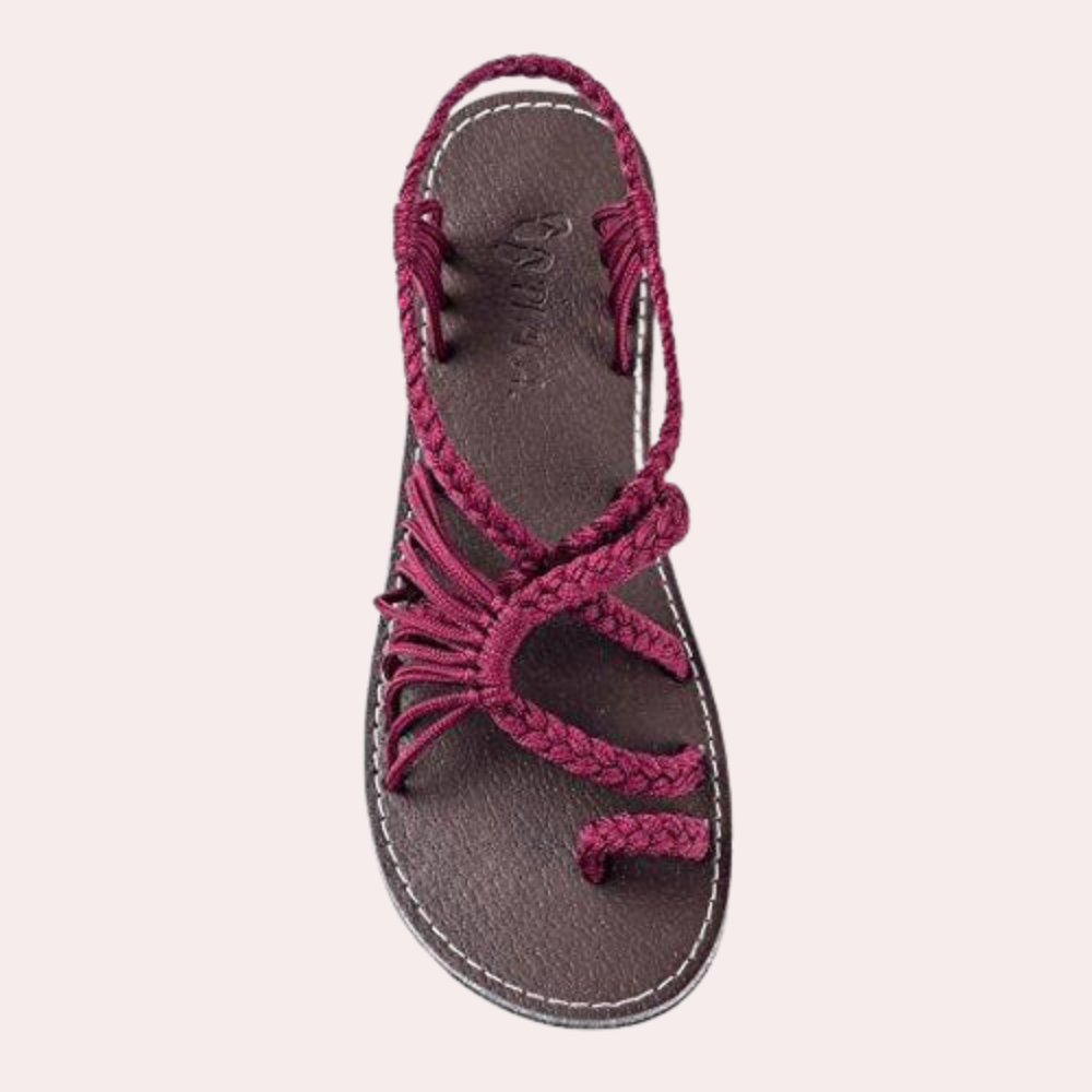 Red braided rope sandal with a flat sole, featuring intricate strap design. Perfect for casual summer wear. Comfortable and stylish footwear option.