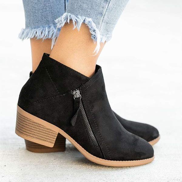 Black suede ankle boots with side zipper, stacked heel, and frayed hem jeans. Stylish women's footwear, comfortable footbed, casual fashion.