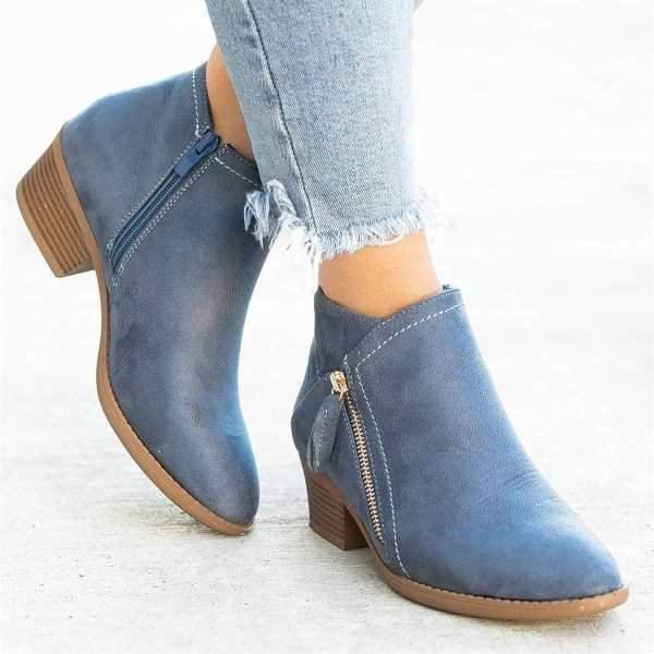 Blue women's ankle boots with side zippers, featuring a high-quality footbed and low block heel, paired with frayed hem jeans. Fashionable footwear.